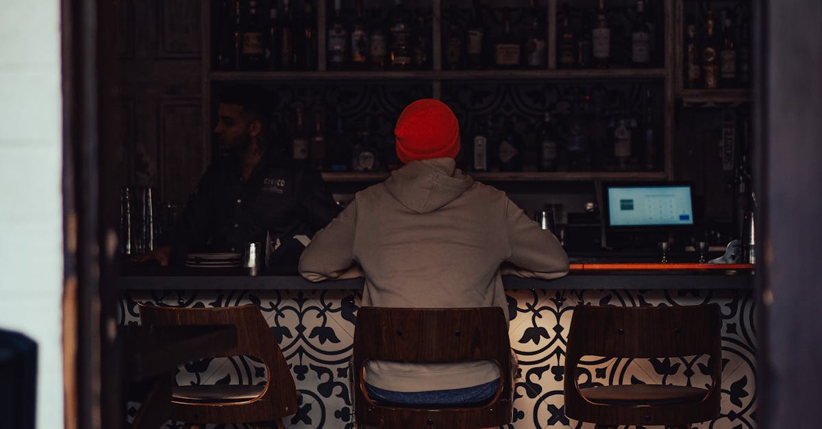 A person watching basketball on TV at a cozy bar with elegant decor.